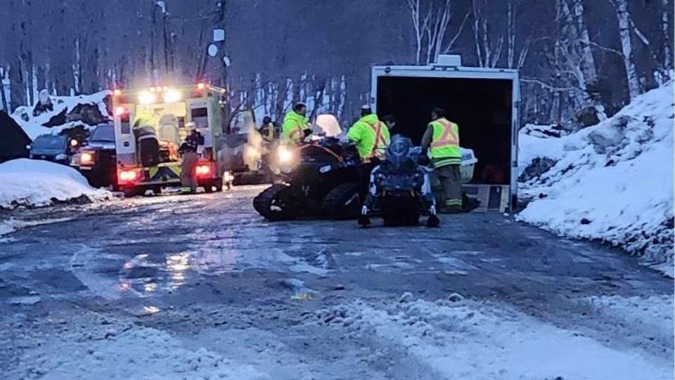 Une équipe de secouristes sur une route l'hiver avec des véhicules d'urgence.