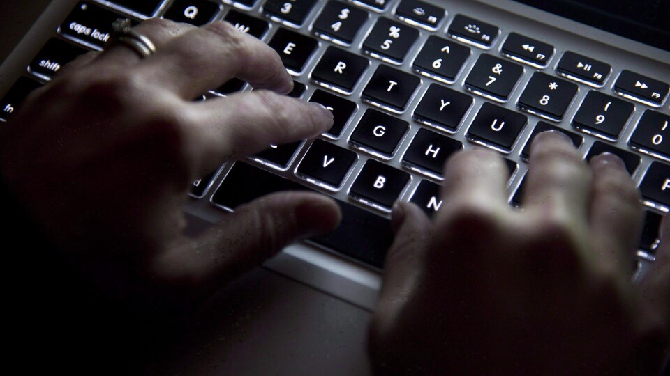 Des mains sur un clavier d'ordinateur.