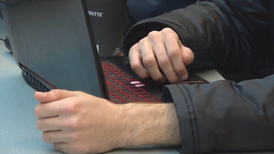 Deux mains devant un ordinateur portable.