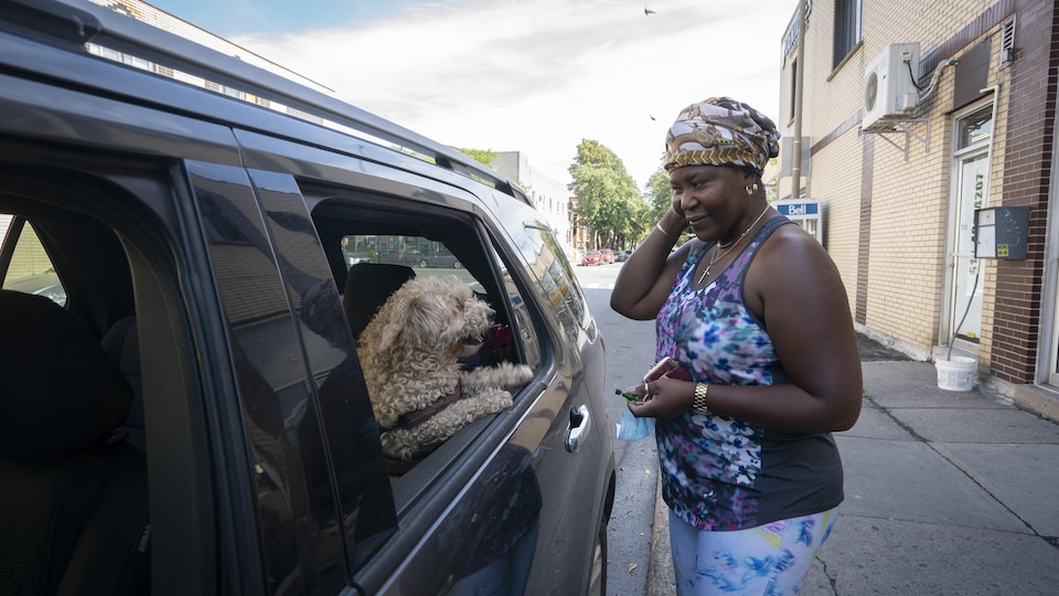 Osako Omba regarde son chien Lolita dans la fenêtre de sa voiture.