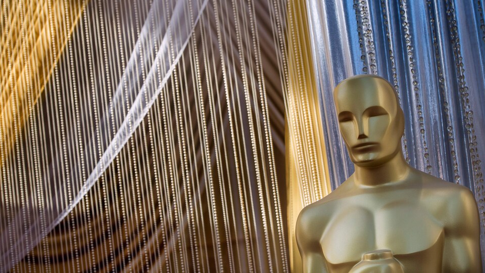 Un Oscar format géant est installé devant des rideaux scintillants.