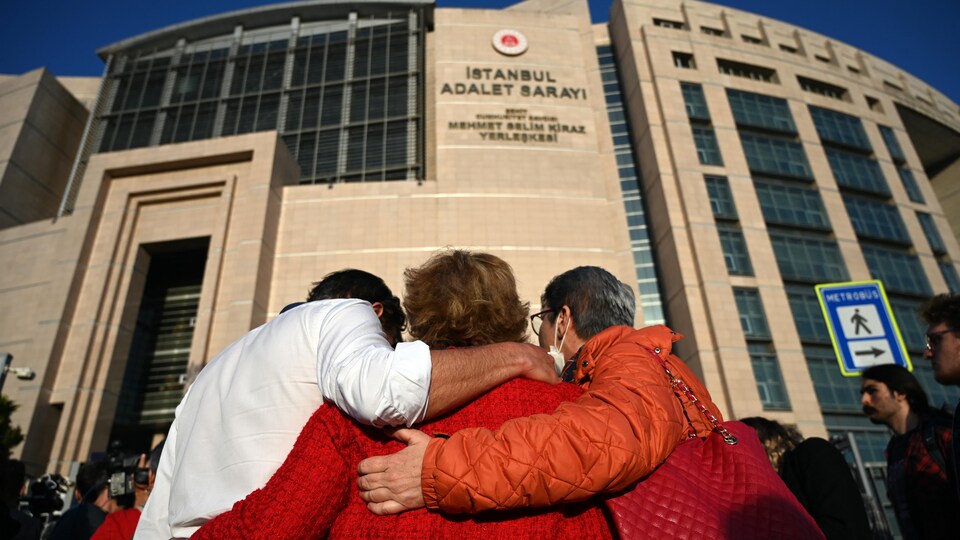 The three people hugged in front of the courthouse. 