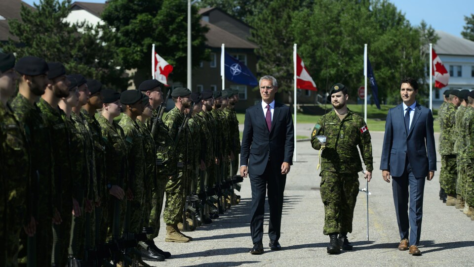 MM. Stoltenberg et Trudeau marchent devant des militaires.