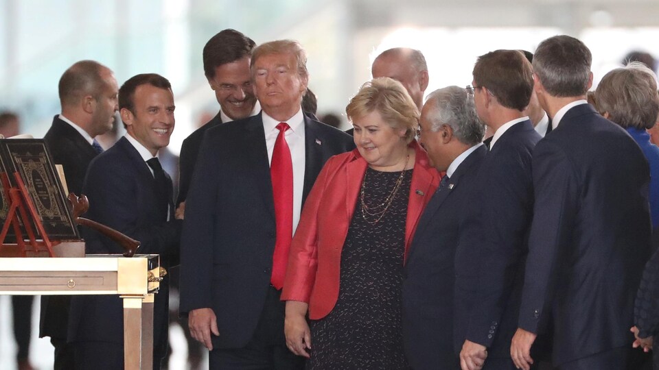 Les trois dirigeants sont entourés d'autres officiels.
