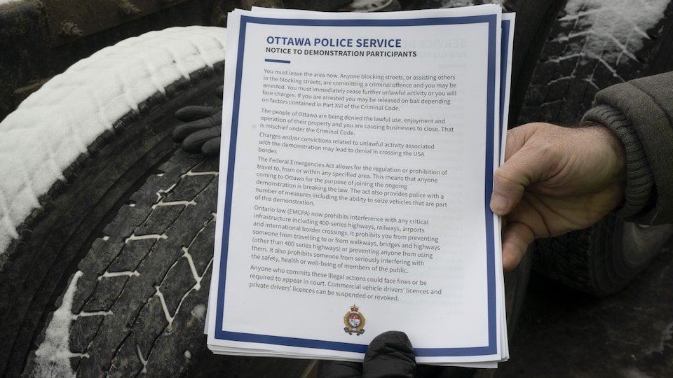 Une main tient un bout de papier qui comporte une entête de la police d'Ottawa.