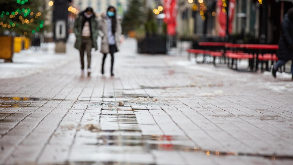 Deux femmes marchent sur la rue Sparks qui est trempée par la pluie.