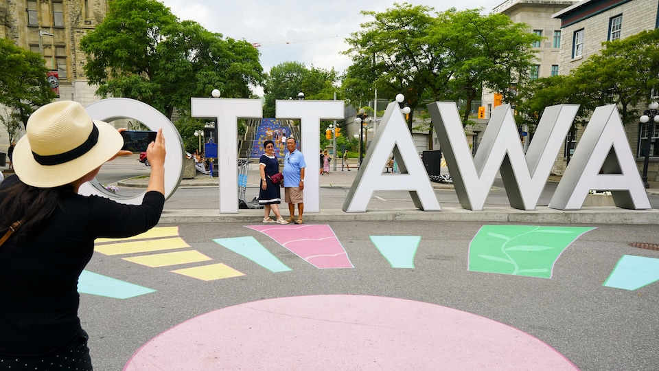 Des touristes posent devant l'insigne «Ottawa» au marché By.