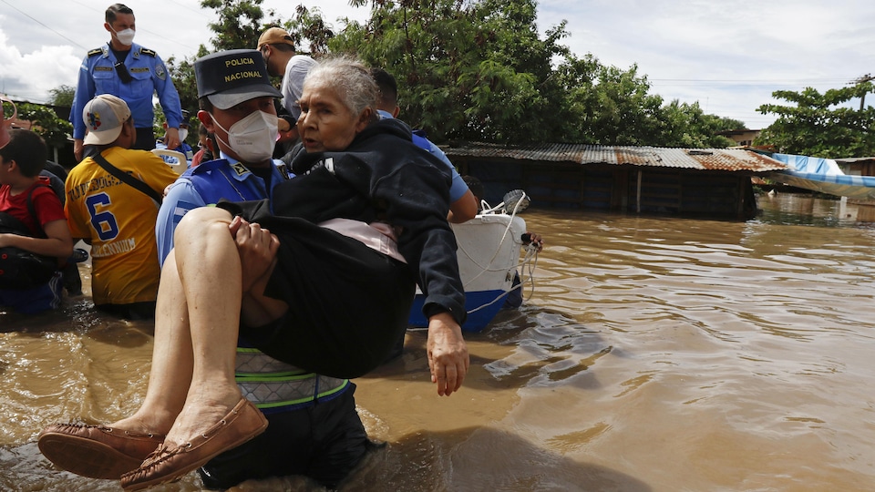 Un agent de la police nationale transporte une dame aînée après le passage de l'ouragan Eta à Jerusalen au Honduras, le 5 novembre 2020.