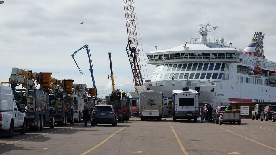 Des camions d'Hydro-Québec devant le traversier à quai, à Souris, à l'Île-du-Prince-Édouard. 