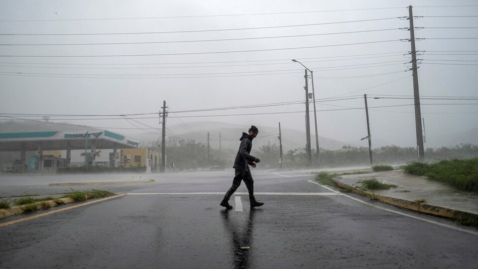 Un jeune homme traverse la rue sous une forte pluie.