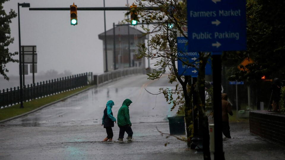 Deux personnes traversent une route inondée en Caroline du Nord.