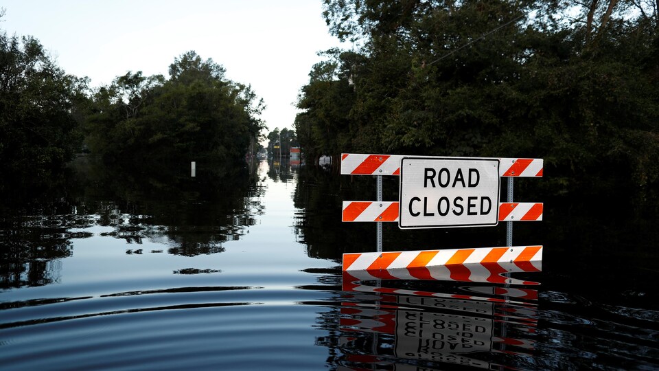 Une route sous les eaux, avec un panneau «road closed».