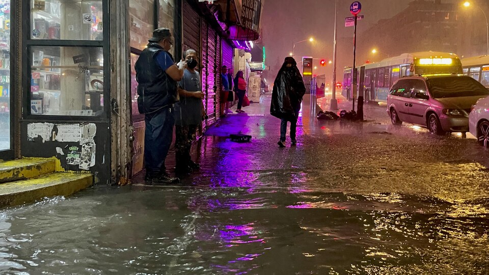 Des gens marchent les pieds dans l'eau dans les rues de New York.