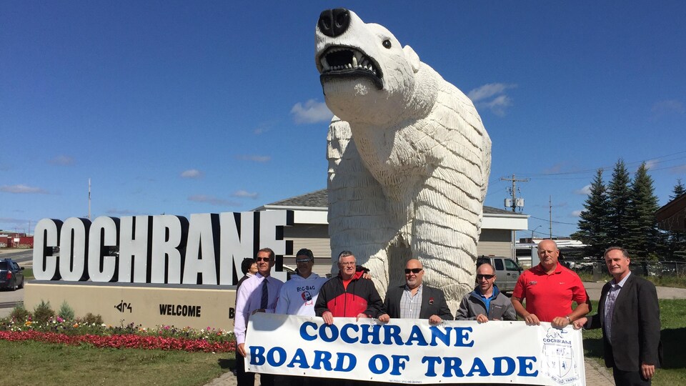 Un groupe de personne posant devant une sculpture d'ours polaire