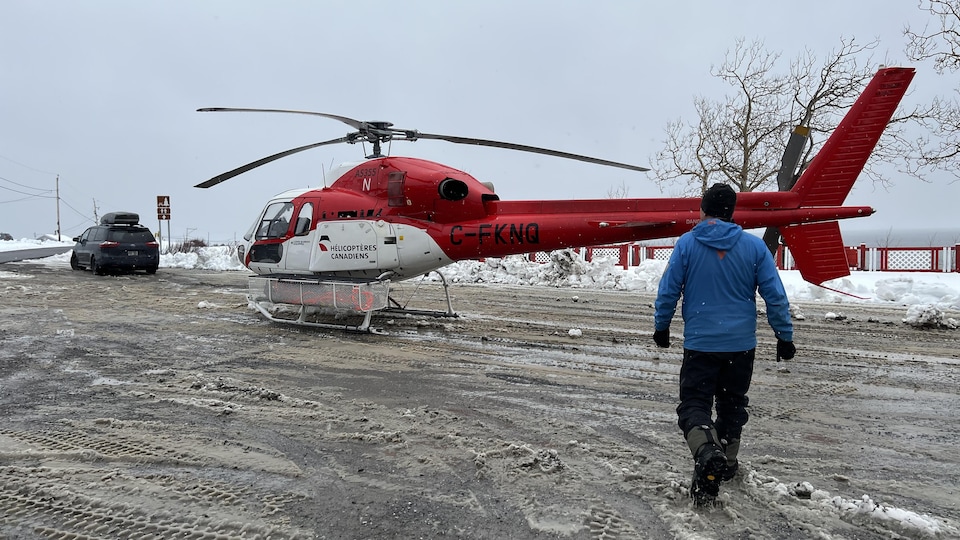 Un homme s'avance vers un hélicoptère des « hélicoptères canadiens ». 