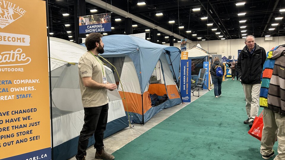 Un homme devant des tentes attend les visiteurs du Outdoor Adventure Show au centre BMO, à Calgary en mars 2023.

