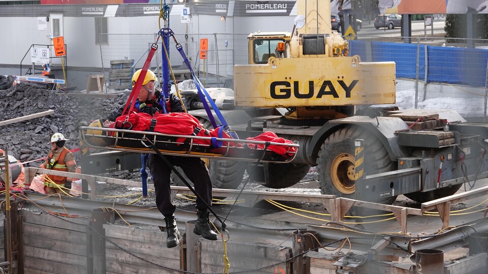 Un pompier sort un homme qui se trouvait au fond d’une tranchée d’excavation à la suite d'un accident de travail survenu sur la rue Berri, à Montréal, le 27 mars 2018.