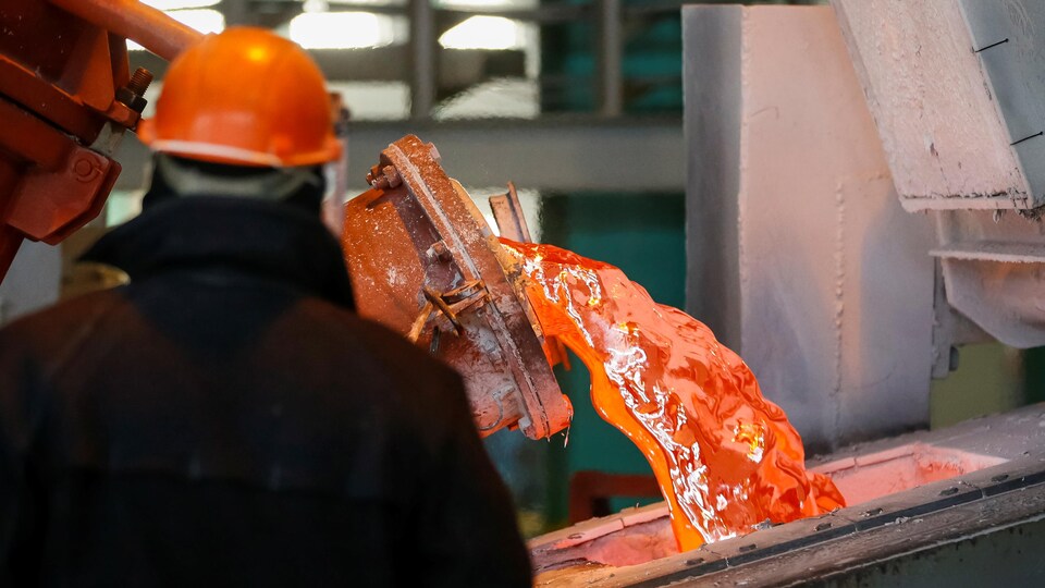 Un ouvrier observe une coulée d’aluminium dans un moule.