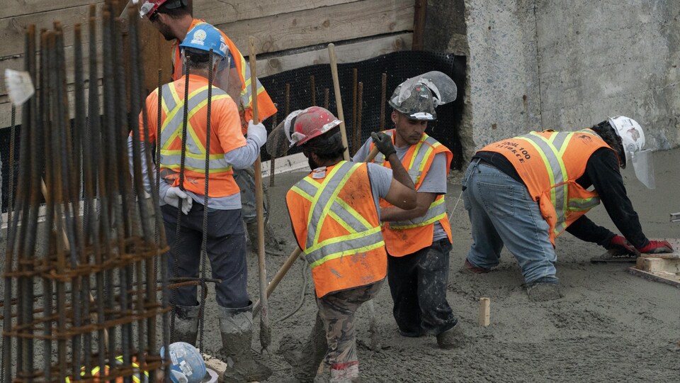 Des ouvriers coulent du ciment sur un chantier. 