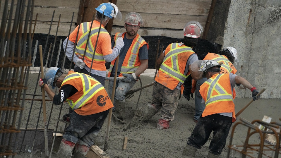 Des ouvriers coulent du ciment sur un chantier.