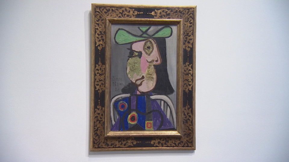 Cadre accroché à un mur présentant un portrait du style cubisme d'une dame assis, portant une robe fleurie et un chapeau vert.