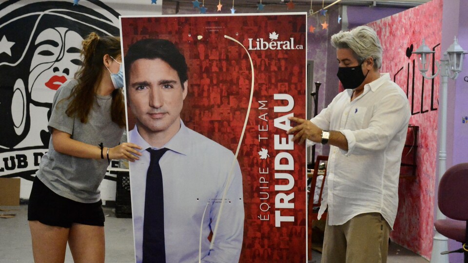 Une bénévole et Pablo Rodriguez tiennent une pancarte du premier ministre Justin Trudeau.