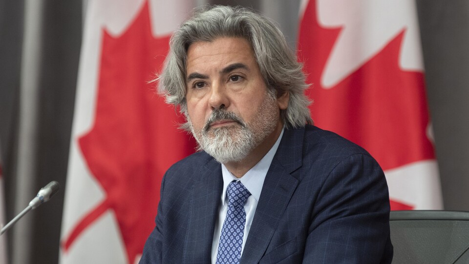 Pablo Rodriguez assis devant des drapeaux du Canada. 