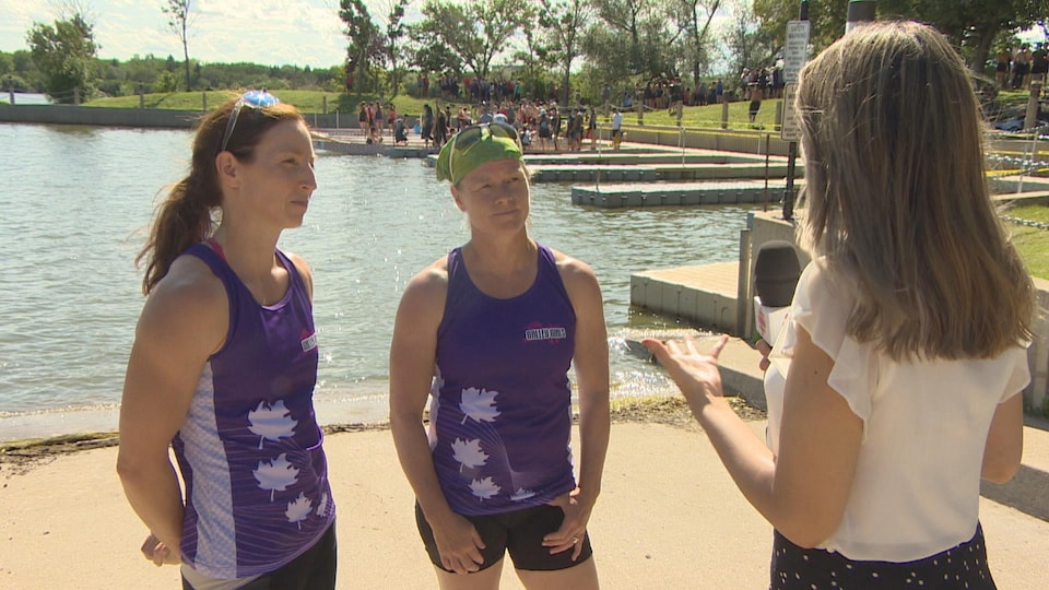 Deux femmes, en tenue de sport, donnent une entrevue près du lac Wascana.