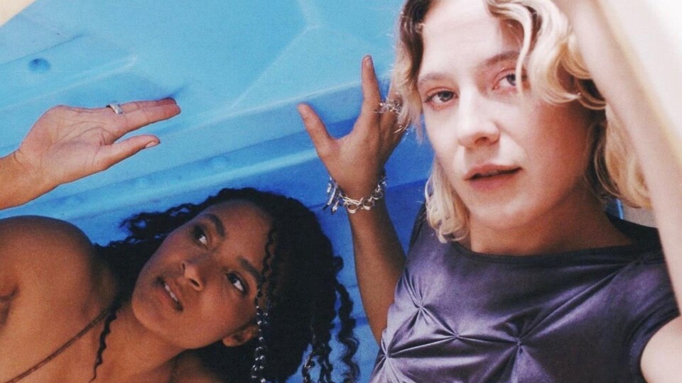 Deux femmes se tiennent sous ce qui semble être un pédalo renversé.