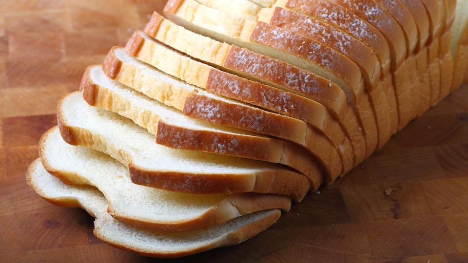 Du pain italien tranché est disposé sur une planche de bois.