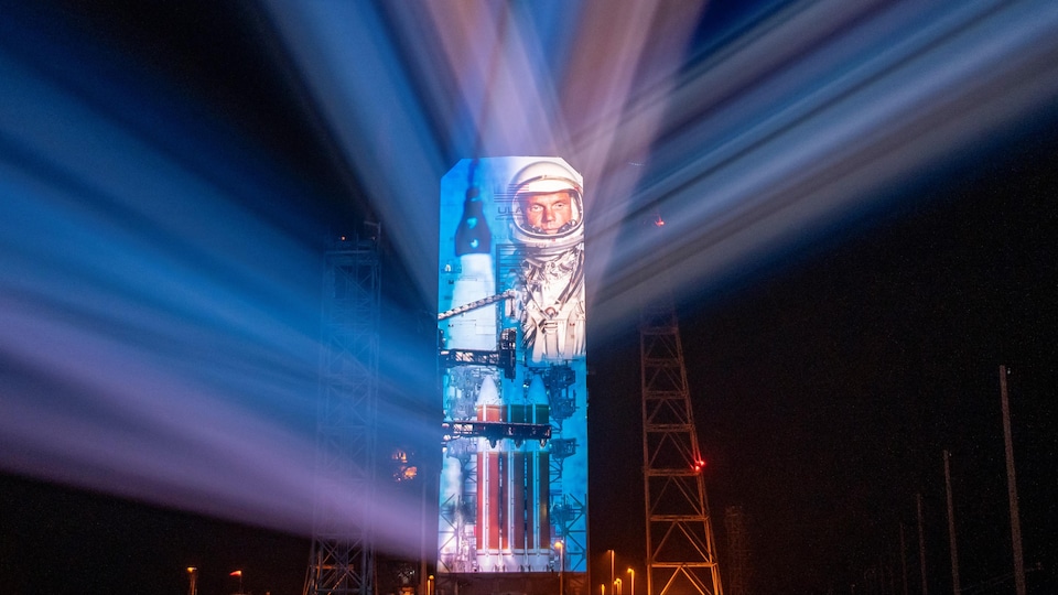 On voit une image de John Glenn sur la rampe de lancement.