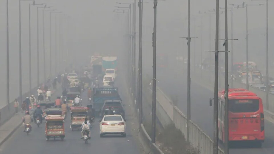 Des véhicules roulant sur une autoroute enveloppée par le smog.