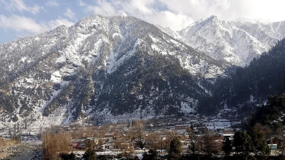 Le village de Kundal Shahi, au pied des montagnes, est couvert de neige.