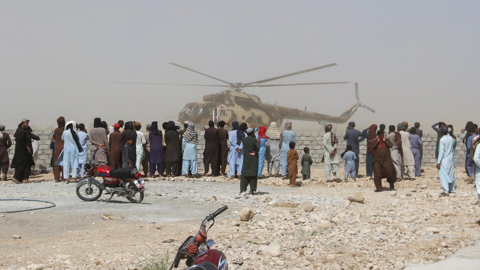 Une foule attend près d'un hélicoptère de l'armée.
