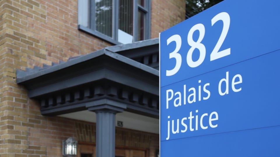 Panneau annonçant le palais de justice avec un bâtiment en arrière-plan.