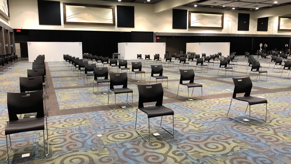 Des centaines de chaises sont alignées dans une vaste salle de conférence.