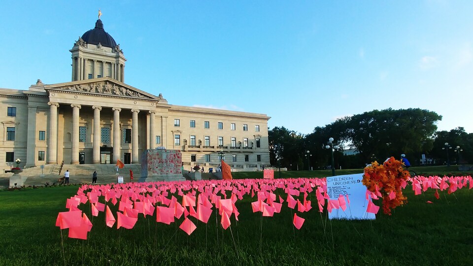 Le socle sur lequel se trouvait la statue de la reine Victoria devant le Palais législatif du Manitoba, à Winnipeg, est vide. Des petits drapeaux sont plantés devant.