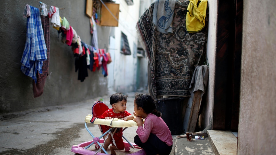 Une jeune fille joue avec son frère dans un camp de réfugiés, dans la bande de Gaza.