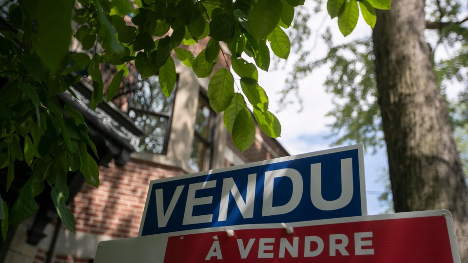 Une pancarte immobilière sur laquelle on peut lire Vendu.