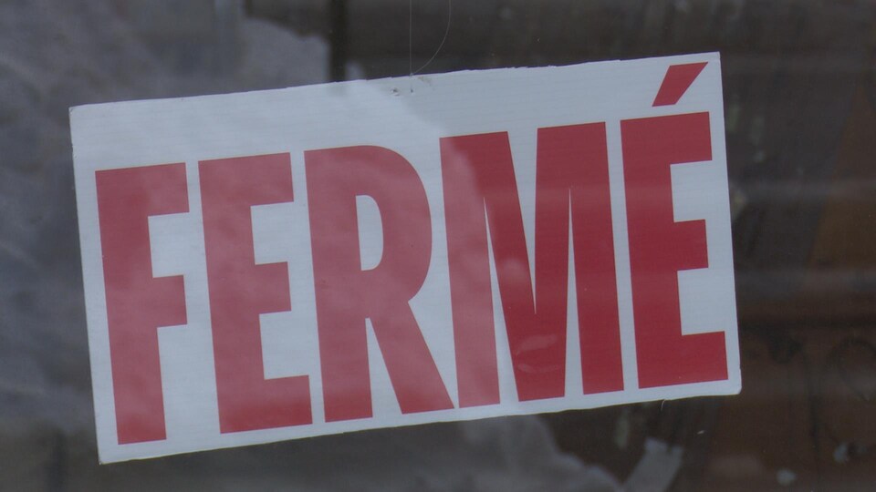Une pancarte affichant fermé collé sur une vitre.