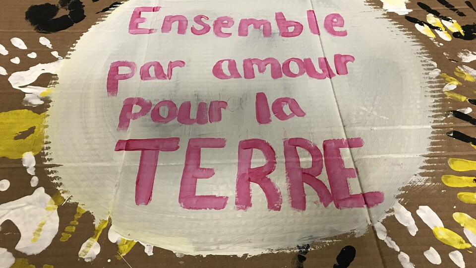 Sur l'affiche réalisée par les élèves de l'École Mitchell-Montcalm, ils ont peint les mots « Ensemble par amour pour la Terre », sur un grand rond blanc, et laissé l'empreinte de leurs mains.