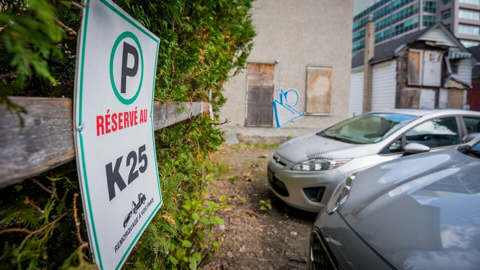 Un panneau indique que l'espace de stationnement est réservé au K25. Deux voitures  sont garées tout près. 