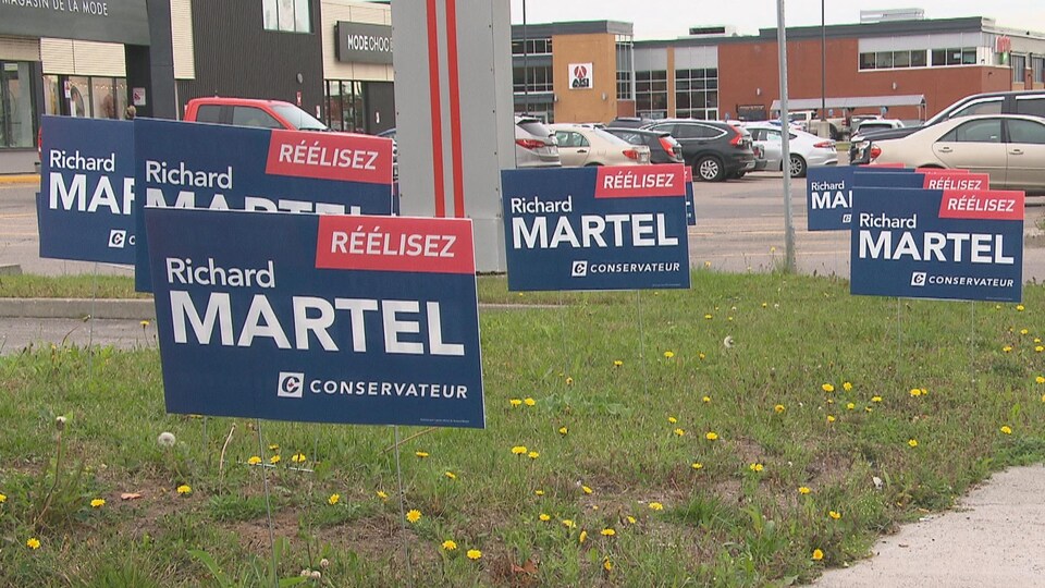 Des pancartes électorales ont été installées à proximité d'un stationnement commercial.
