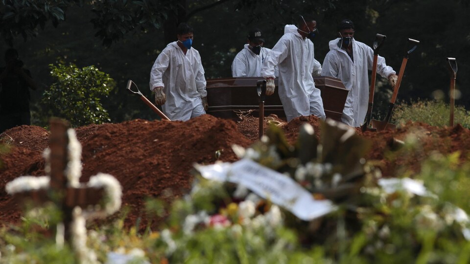 Des employés du cimetière portent le cercueil d'une victime de la COVID-19 au cimetière de Vila Formosa à Sao Paulo