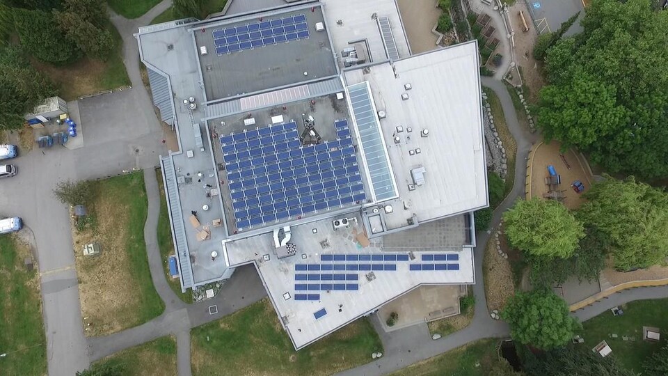 Vue aérienne du toit d'un bâtiment sur lequel sont installés plus d'une centaine de panneaux solaires.