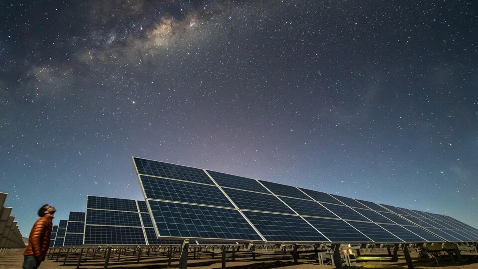Des rangées de panneaux solaires dans un désert, la nuit.