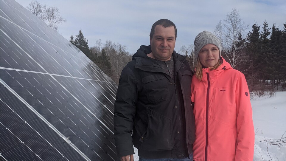 Guylain Bernard et Nathalie Leduc près de leurs panneaux solaires sur leur terrain.