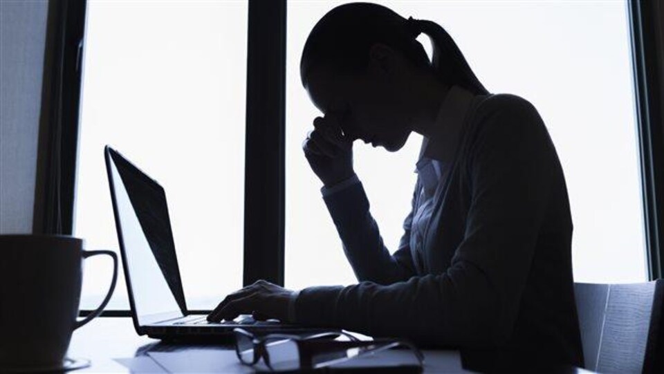 Une femme au travail se tient la tête devant son ordinateur.