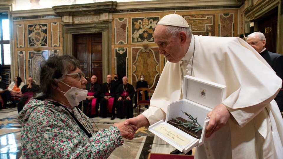 Le pape tient dans une main un écrin contenant une sculpture et serre de l'autre main celle d'une femme.