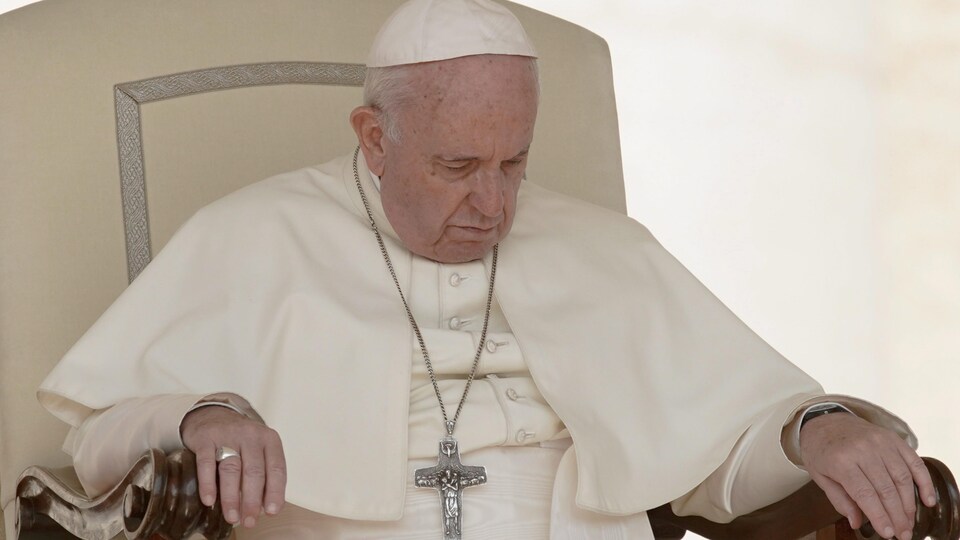 Le pape François, yeux fermés, tête baissée, est assis dans un fauteuil.
